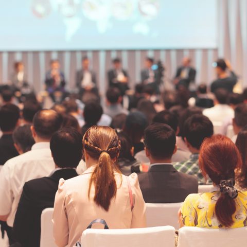 Rear view of Audience in the conference hall or seminar meeting which have Speakers on the stage